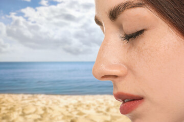 Obraz premium Beautiful young woman with freckles on beach, closeup