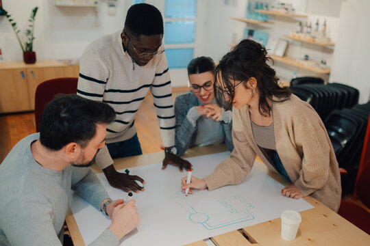 Diverse team drawing app prototype on whiteboard during brainstorming session