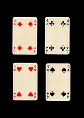 A hand of antique playing cards showing four of the same value.