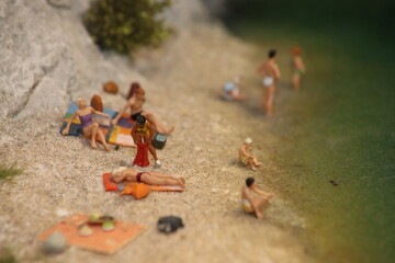 Miniaturmenschen im Badeanzug am Strand