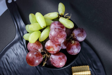 Assorted snacks with fresh grapes, cheese slices, square crackers, and cherry tomatoes, beautifully...