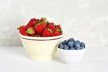 Two bowls with fresh strawberries and blueberries