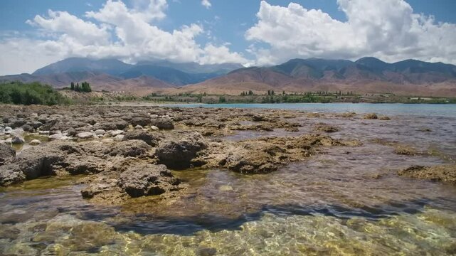 Footage showcasing the rugged stone coastline of Assyk Kul Lake, with a focus on the natural elements of the shoreline and crystal-clear waters in Kyrgyzstan.