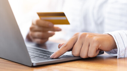 Unrecognizable millennial person shopping in internet on personal computer, using credit card to pay, closeup