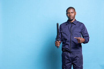 Trained security personnel pointing at his police baton in studio, presenting his weapon to use in...