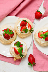 Meringue nests mini pavlovas with whipped cream and strawberries on a plate.top veiw