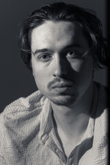 Portrait of a contemplative young man in soft shadows showcasing introspection and depth during a quiet evening indoors