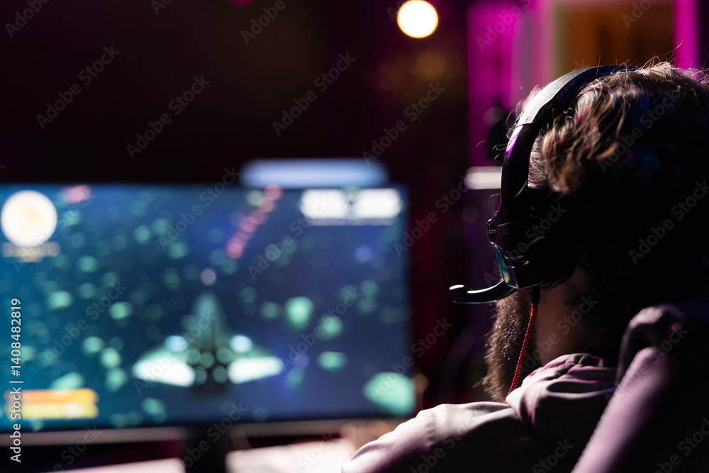 Poster man using headphones to communicate with teammates while playing first person shooter videogame with