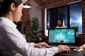 Female business analyst using her personal computer to examine marketing trends and track company...