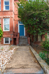 Detail of the entrance to a brick house with steps leading up to the blue front door.