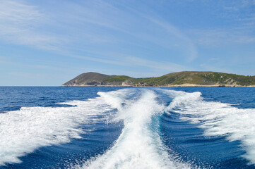 Speed boat wake at Adriatic sea near Vis island coast with Bisevo island in background