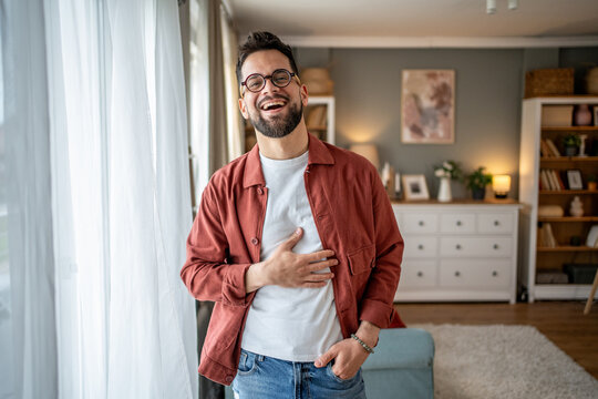 Cheerful man laughing holding his stomach at home