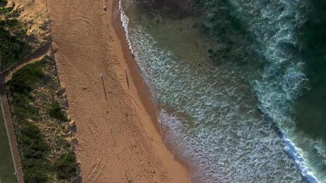 Stunning drone footage of Mona Vale Beach at sunrise, showcasing golden cliffs, serene waves, and the iconic ocean rockpool on Sydney&rsquo;s Northern Beaches.