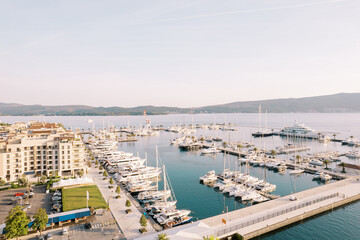 Fototapeta premium Large marina with rows of yachts moored off the shore with expensive hotels. Porto, Montenegro. Drone