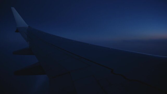 The breathtaking view from an airplane window during a night flight beautifully showcases the aircrafts wing against a stunning dark sky
