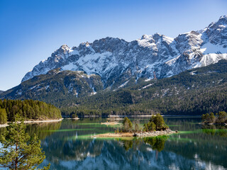 A view of Lake Ebsee in Germany with its emerald green water and a tiny island in the middle....