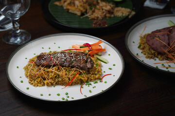 Grilled Sliced Beef over Fried Rice with Steamed Vegetables and Fresh Garnishes