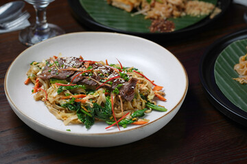 Stir-Fried Beef Noodles with Fresh Vegetables and Sesame Garnish