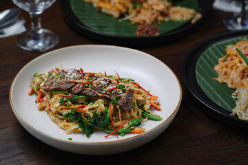 Stir-Fried Beef Noodles with Fresh Vegetables and Sesame Garnish