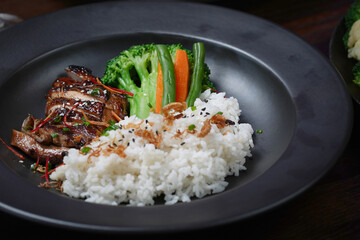 Grilled Teriyaki Chicken with Steamed Rice and Vegetables on a Black Plate