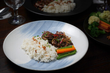 Grilled Teriyaki Chicken with Steamed Rice and Vegetables on a Black Plate