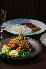 Braised and Grilled Lamb Shank with Delicious Spices and Steamed Vegetables on a Black Plate