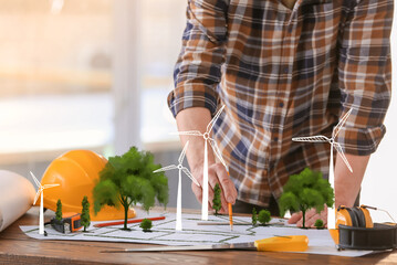 Engineer with drawing of windmill power plant in office, closeup. Green technology concept