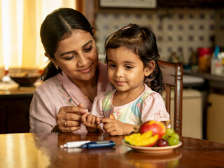 A young diabetic patient having her blood sugar tested by her mother. 