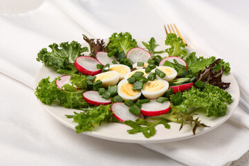 Plate of tasty salad with fresh vegetables and boiled quail eggs on light background