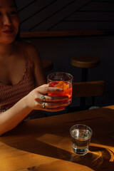 young woman holding Negroni cocktail in the sun