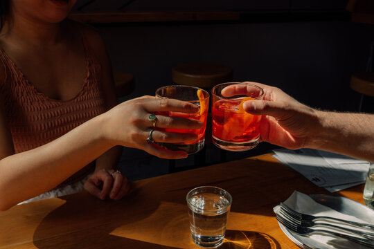 woman and man toasting with two negroni cocktails during happy hour