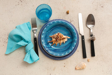 Beautiful table setting with seashells on beige grunge background