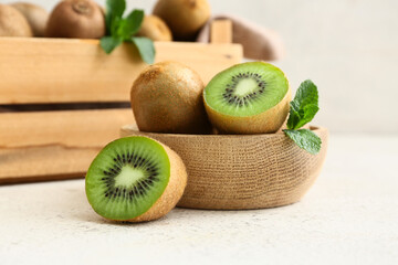 Wooden bowl and box with fresh kiwi on white background
