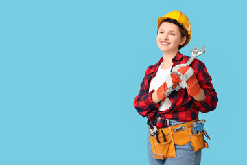 Young female carpenter with wrench on blue background. Labor Day celebration