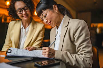 caucasian businesswoman give to japanese female client contract to sign