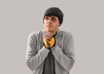 Frozen young homeless man on light background
