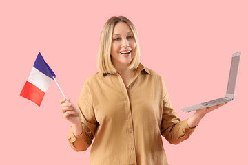 Female French language teacher with flag and laptop on pink background