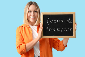 Female French language teacher with small blackboard on blue background