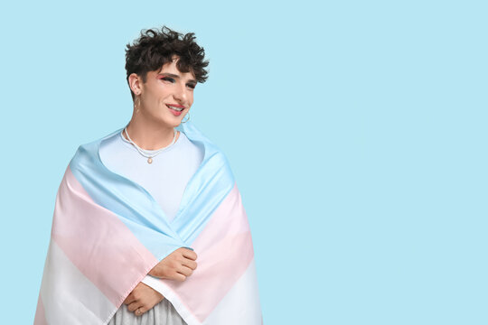 Young transgender woman with flag on blue background - Powered by Adobe