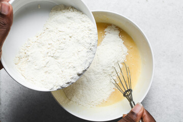 Overhead view of flour being mixed into cake batter, top view of vanilla cake batter being mixed, process of making vanilla cake