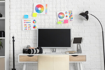 Photographer workplace with computer, color wheel charts and photo cameras in modern studio