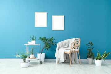 Blurred view of living room with wicker chair, table and different houseplants near blue wall