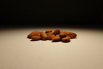 Natural almonds arranged on a beige surface under moody lighting. Minimalist composition with soft shadows, ideal for themes of healthy eating, vegan snacks, or organic lifestyle visuals