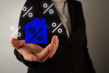 A woman is holding a blue house with a percent inside. Concept of real estate