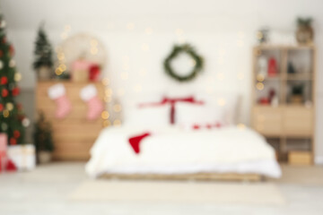 Blurred view of light bedroom with Christmas trees, drawers and shelf unit