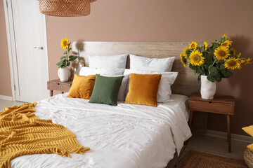 Stylish bedroom with vases of sunflowers bouquets on bedside tables