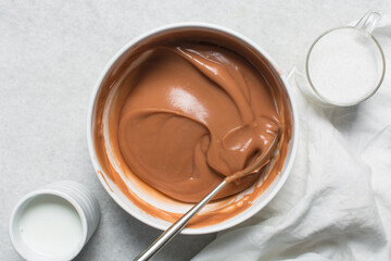 Overhead view of nigerian akamu being made in a white bowl, pap akamu or ogi in a white bowl, top view of nigerian guinea corn pudding in a white ramekin