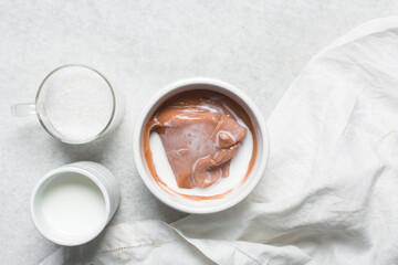 Overhead view of nigerian akamu being made in a white bowl, pap akamu or ogi in a white bowl, top view of nigerian guinea corn pudding in a white ramekin