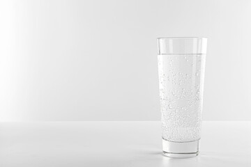 Refreshing soda water in glass on white table against light background. Space for text