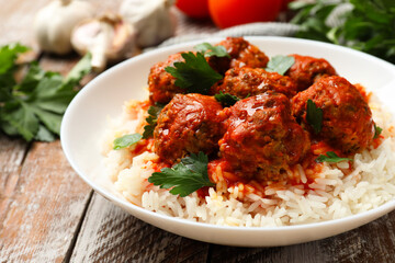Tasty meatballs with sauce, rice and products on wooden table, closeup